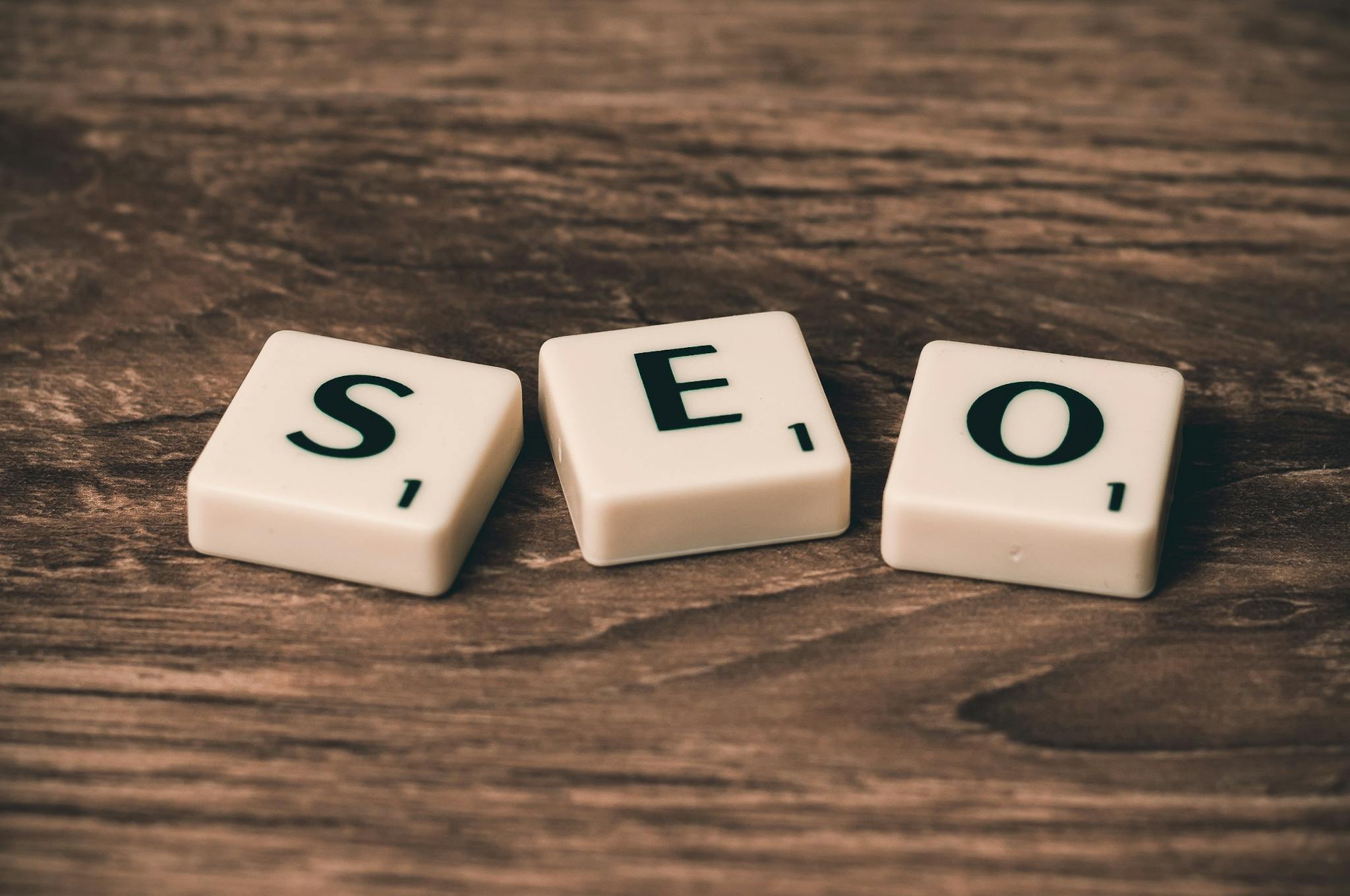 Scrabble tiles spelling 'SEO' on a wooden surface. Ideal for digital marketing themes for SEO services